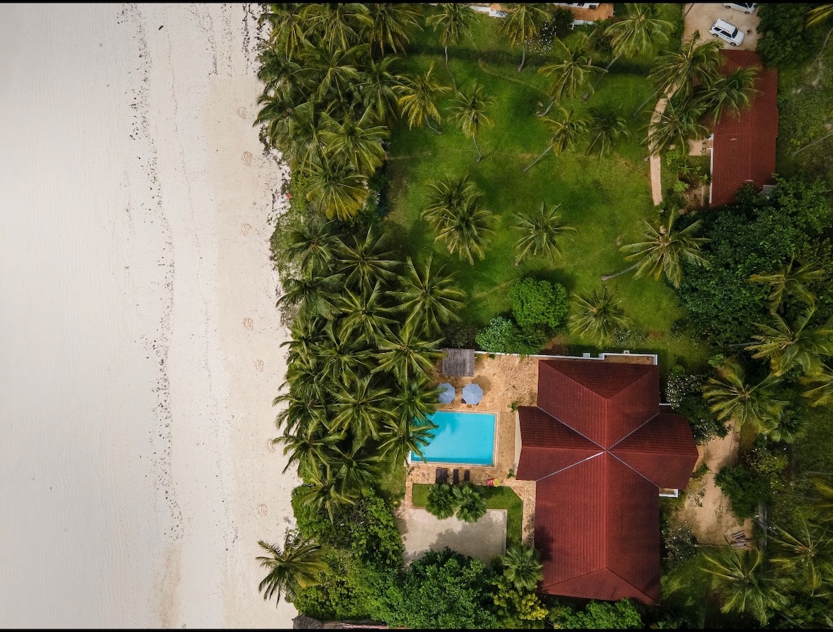 Overhead aerial showing villa, pool and beach directly adjacent